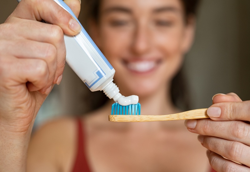 A girls hand squeezing toothpaste on ecological wooden brush in McAllen, TX